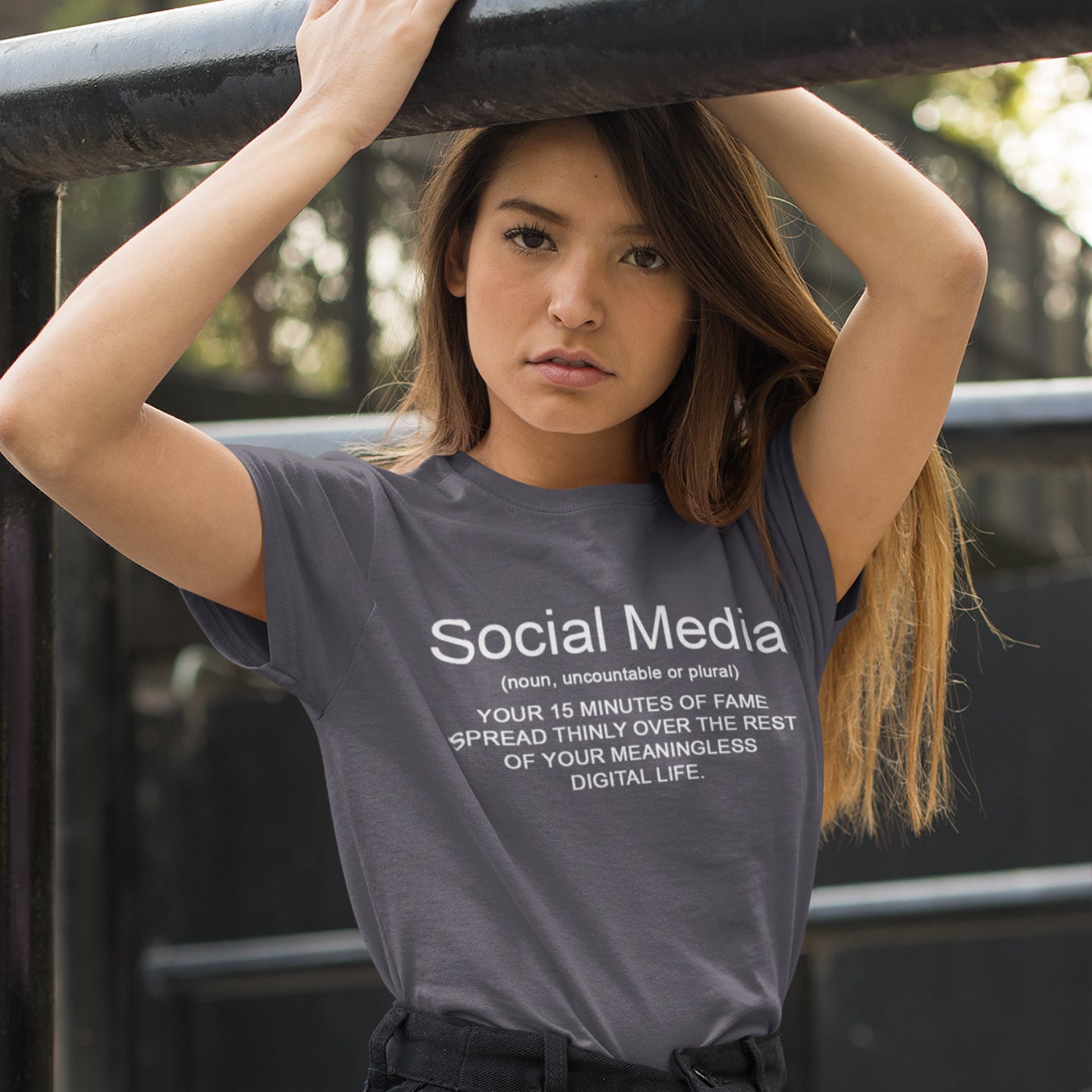 Person wearing a t-shirt with a social media definition print, standing outdoors. An anti-social media t-shirt with a humorous definition. A unique t-shirt design for those who still have a real life and consider 'community' to be something you can touch and walk around. Made from 100% organic ring-spun cotton, this anti social media t-shirt is unisex, high-quality, super comfy, and best of all, eco-friendly.
