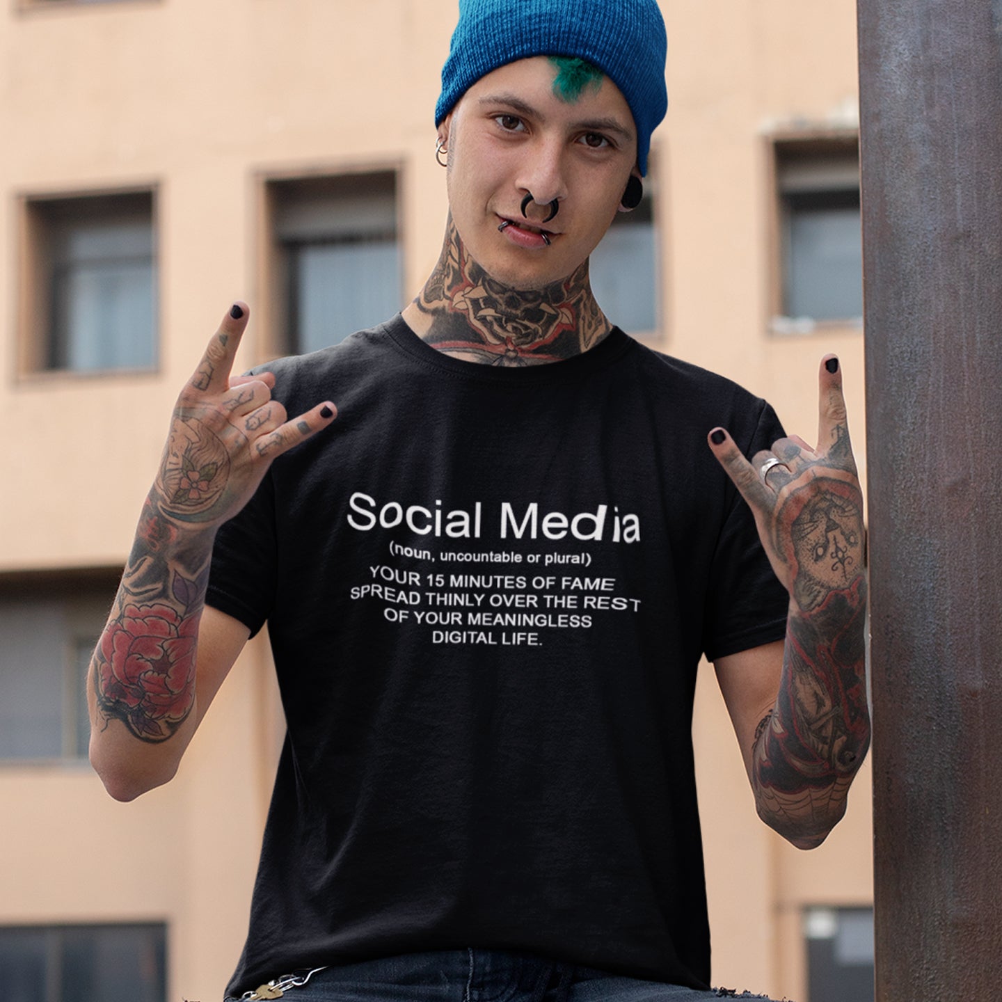 Person wearing a black t-shirt with social media definition text, making hand gestures outdoors. An anti-social media t-shirt with a humorous definition. A unique t-shirt design for those who still have a real life and consider 'community' to be something you can touch and walk around. Made from 100% organic ring-spun cotton, this anti social media t-shirt is unisex, high-quality, super comfy, and best of all, eco-friendly.