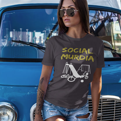 Woman wearing a t-shirt with 'Social Murdia' design in front of a blue vintage car. This counterculture t-shirt promoting social awareness of the effect of social media on our children. A unique design depicting how social media is probably murdering our society and leaving our playgrounds empty. Made from 100% organic ring-spun cotton, this anti-mobile phone t-shirt is unisex, high-quality, super comfy, and best of all, eco-friendly.
