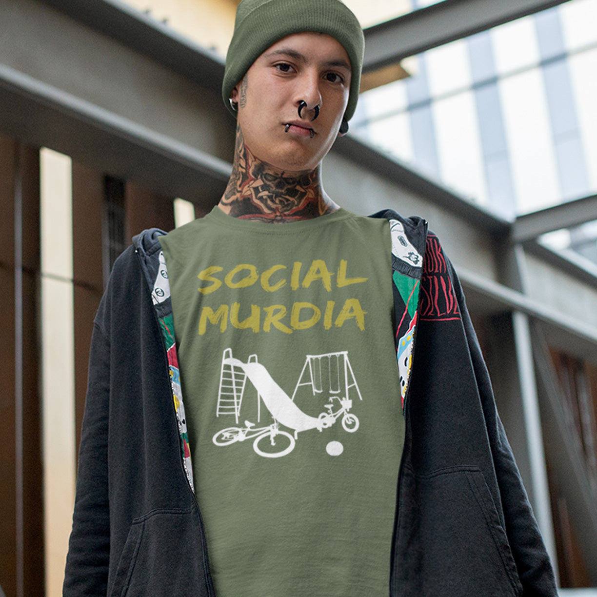 Person wearing a khaki t-shirt with 'SOCIAL MURDIA' text and graphic design. This anti mobile phone abuse t shirt promoting social awareness of the effect of social media on our children. A unique design depicting how social media is probably murdering our society and leaving our playgrounds empty. Made from 100% organic ring-spun cotton, this anti social media t shirt is unisex, high-quality, super comfy, and best of all, eco-friendly.