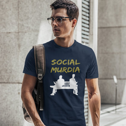 A man wearing a French navy blue graphic t-shirt with the words 'SOCIAL MURDIA' in yellow and a white graphic below, standing in front of a grey stone wall.
