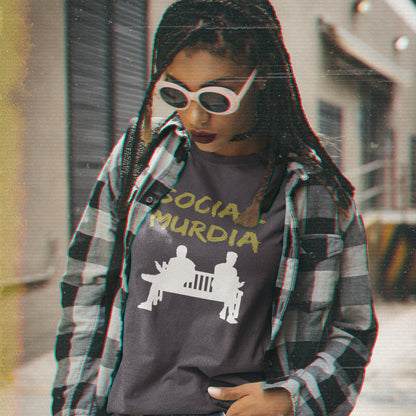 Person wearing a graphic t-shirt with text and design, standing outdoors. An anti-social media t-shirt arguing against the abuse of social media and mobile phones.  This anti-mobile phone design suggests society is actually being murdered by media on mobiles. Made from 100% organic ring-spun cotton, this anti-social media t-shirt is unisex, high-quality, super comfy, and best of all, eco-friendly.