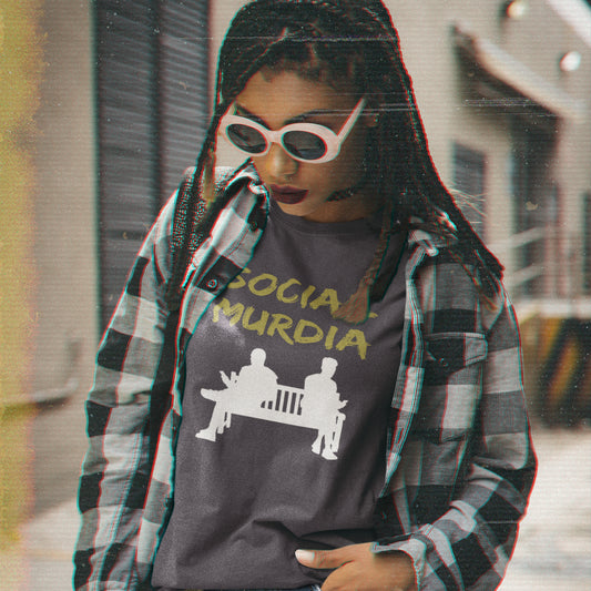 Person wearing a graphic t-shirt with text and design, standing outdoors. An anti mobile phone abuse t shirt arguing against the abuse of social media and mobile phones. The main aim of social media is to connect people, but it doesn't look like that from street level. This anti-mobile phone design suggests society is actually being murdered by media on mobiles. Made from 100% organic ring-spun cotton, this anti social media t shirt is unisex, high-quality, super comfy, and best of all, eco-friendly.