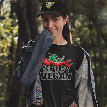 Person wearing a black 'Spicy Vegan' t-shirt with a chili pepper graphic outdoors. A vegan dairy free t shirt design for all you chilli loving spicy vegans out there. Spicy up your wardrobe with this unique funny plant based t-shirt, Made from 100% organic ring-spun cotton, this funny meat free t shirt is unisex, high-quality, super comfy, and best of all, eco-friendly.