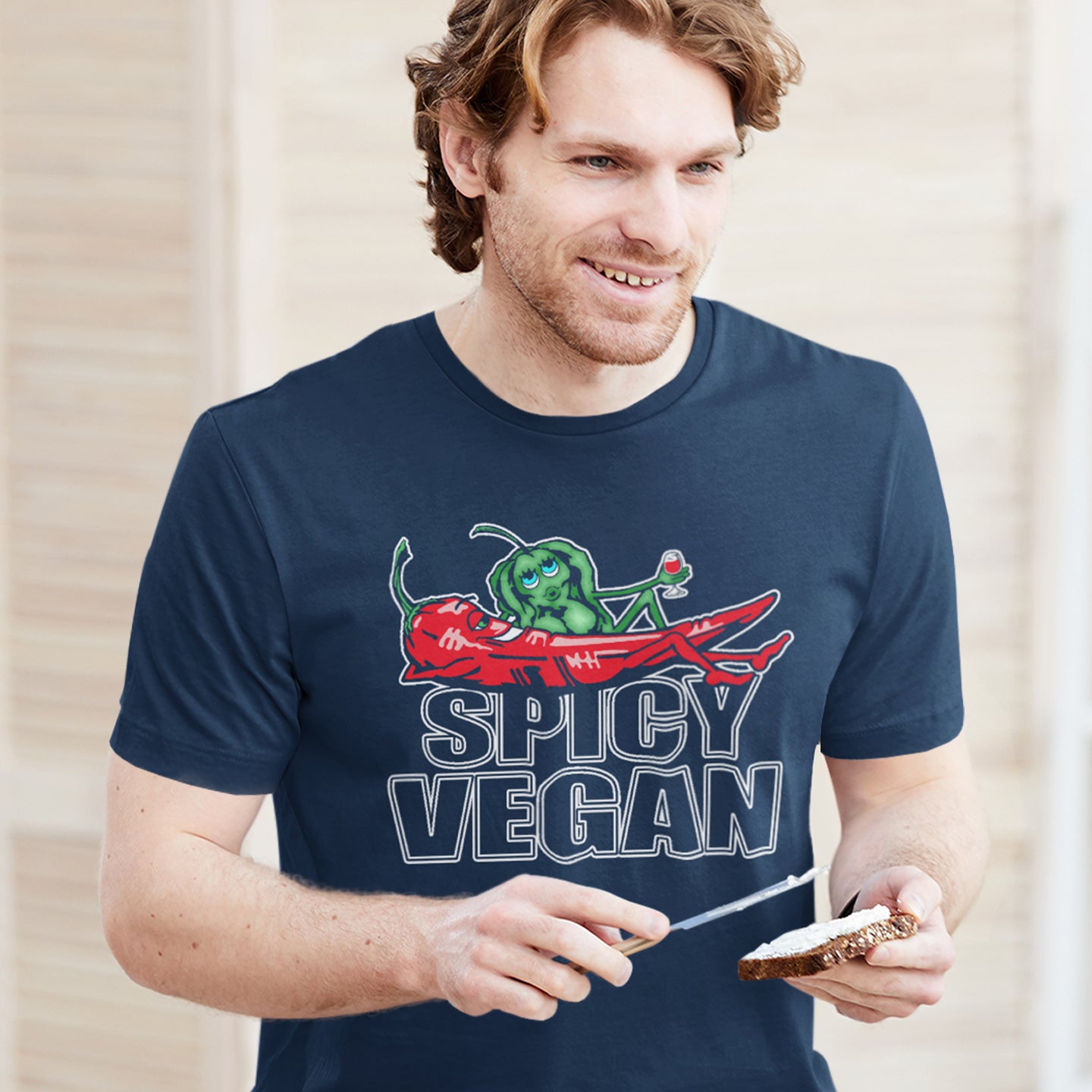 Man wearing a navy blue t-shirt with 'Spicy Vegan' graphic design. A vegan dairy free t shirt design for all you chilli loving spicy vegans out there. Spicy up your wardrobe with this unique funny plant based t-shirt, Made from 100% organic ring-spun cotton, this funny meat free t shirt is unisex, high-quality, super comfy, and best of all, eco-friendly.