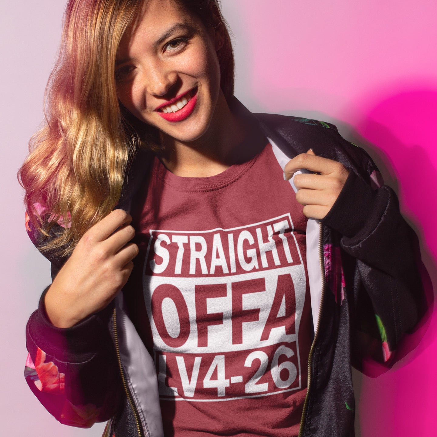 Woman wearing a burgundy t-shirt with text, posing against a pink background. This funny alien t shirt is subtle and loud at the same time. A design for fans of N.W.A and Alien movie lovers. Made from 100% organic ring-spun cotton, this cool sci fi t shirt is unisex, high quality, super comfy, and best of all, eco-friendly.