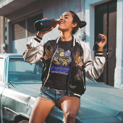 Woman wearing black t-shirt with logo, sitting on a car bonnet drinking from a bottle. A street art graffiti t-shirt design depicting a modern slant on the three wise monkeys. It's time to be street wise. Hear and see everything and have your say. The time for ignorance is over. Made from 100% organic ring-spun cotton, this street art t-shirt is unisex, high-quality, super comfy, and best of all, eco-friendly.