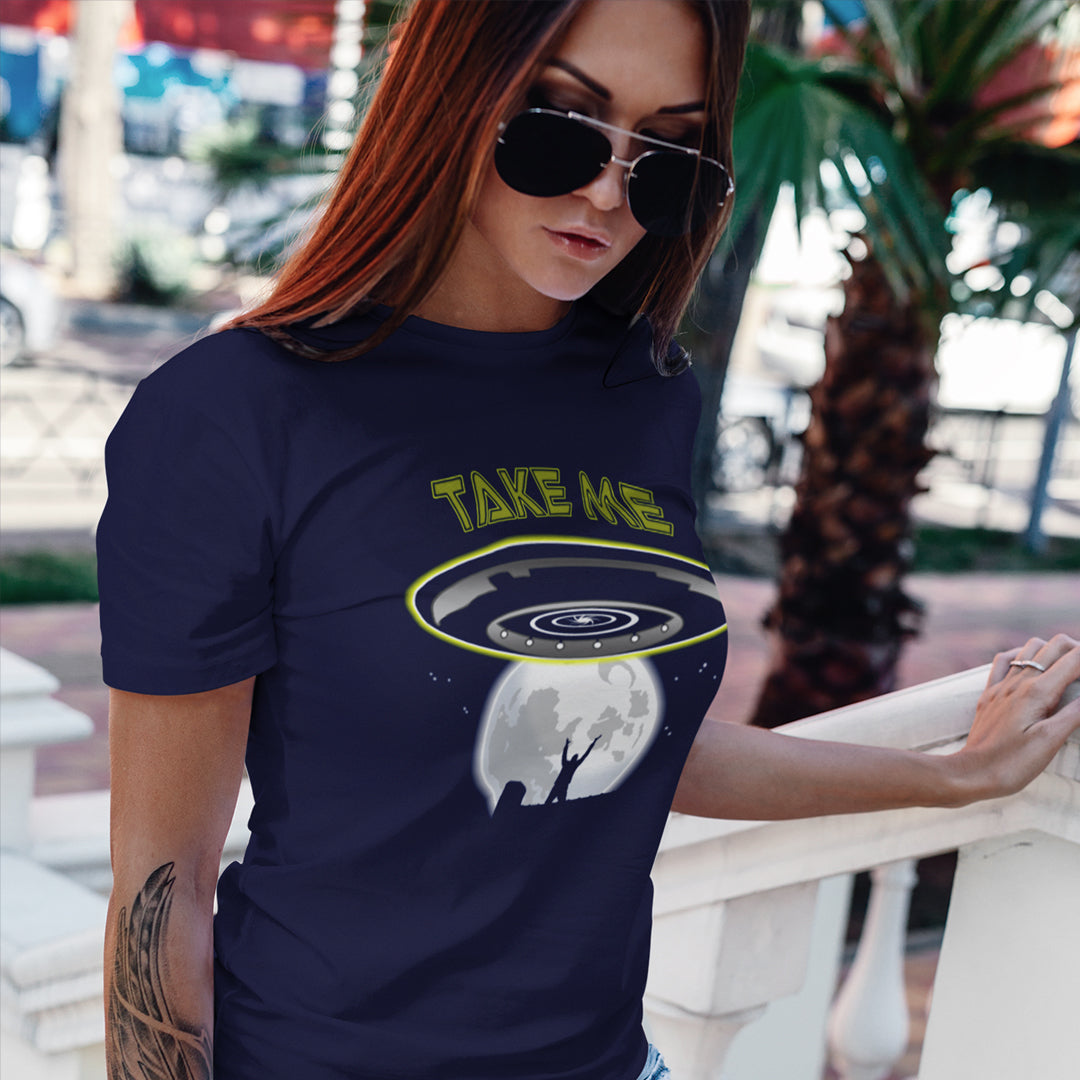 A woman standing outdoors in a French navy coloured t shirt with a spaceship design and "TAKE ME" text.