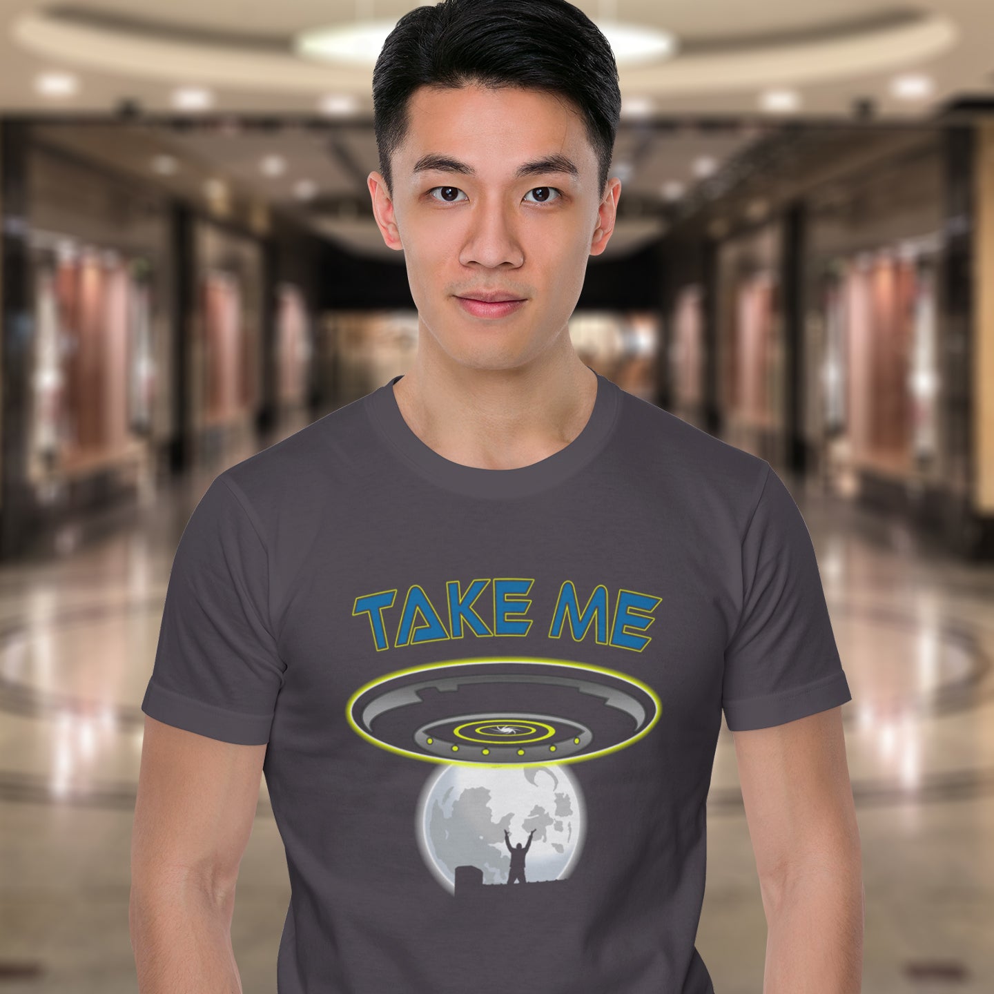 Person wearing a t-shirt with 'TAKE ME' graphic design in a mall setting. This funny alien abduction t-shirt is a must for everyone who feels they have you had enough of this planet or, more to the point, the human race. Do you sometimes think you would be better off being abducted ? Made from 100% organic ring-spun cotton, this funny sci fi t-shirt is unisex, high-quality, super comfy, and best of all, eco-friendly.