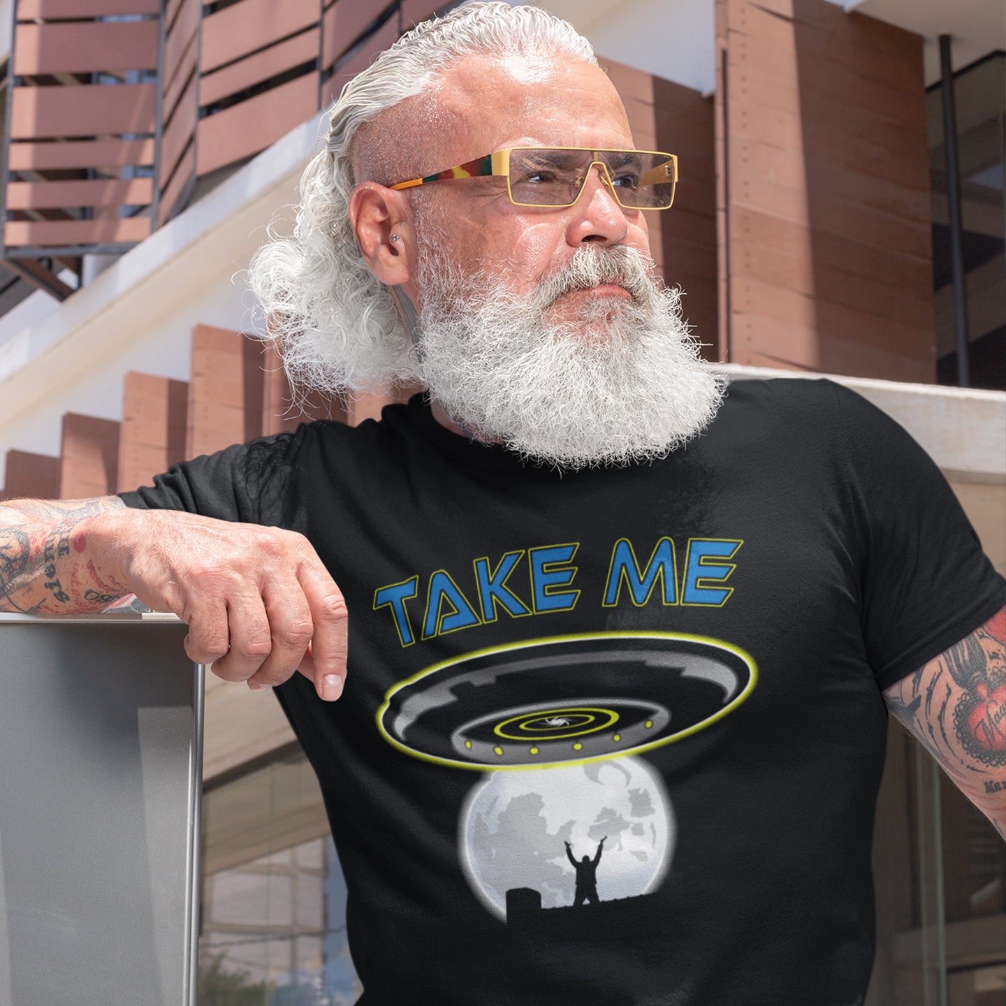 Man wearing a black t-shirt with 'TAKE ME' and UFO design, standing outdoors. This funny alien abduction t-shirt is a must for everyone who feels they have you had enough of this planet or, more to the point, the human race. Do you sometimes think you would be better off being abducted ? Made from 100% organic ring-spun cotton, this funny sci fi t-shirt is unisex, high-quality, super comfy, and best of all, eco-friendly.