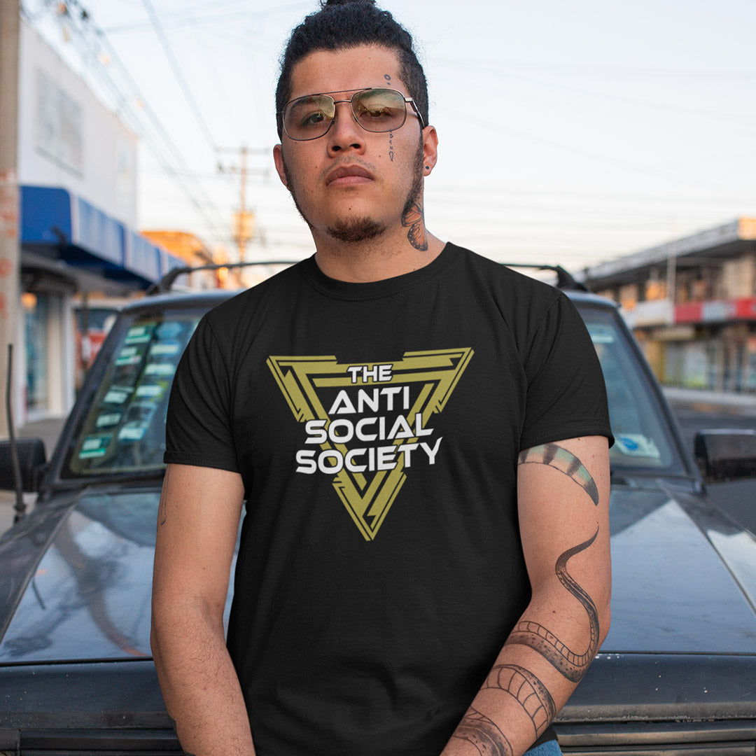 A man wearing a black t-shirt with a yellow and white graphic that reads 'THE ANTI SOCIAL SOCIETY' stands in front of a black car on a street.