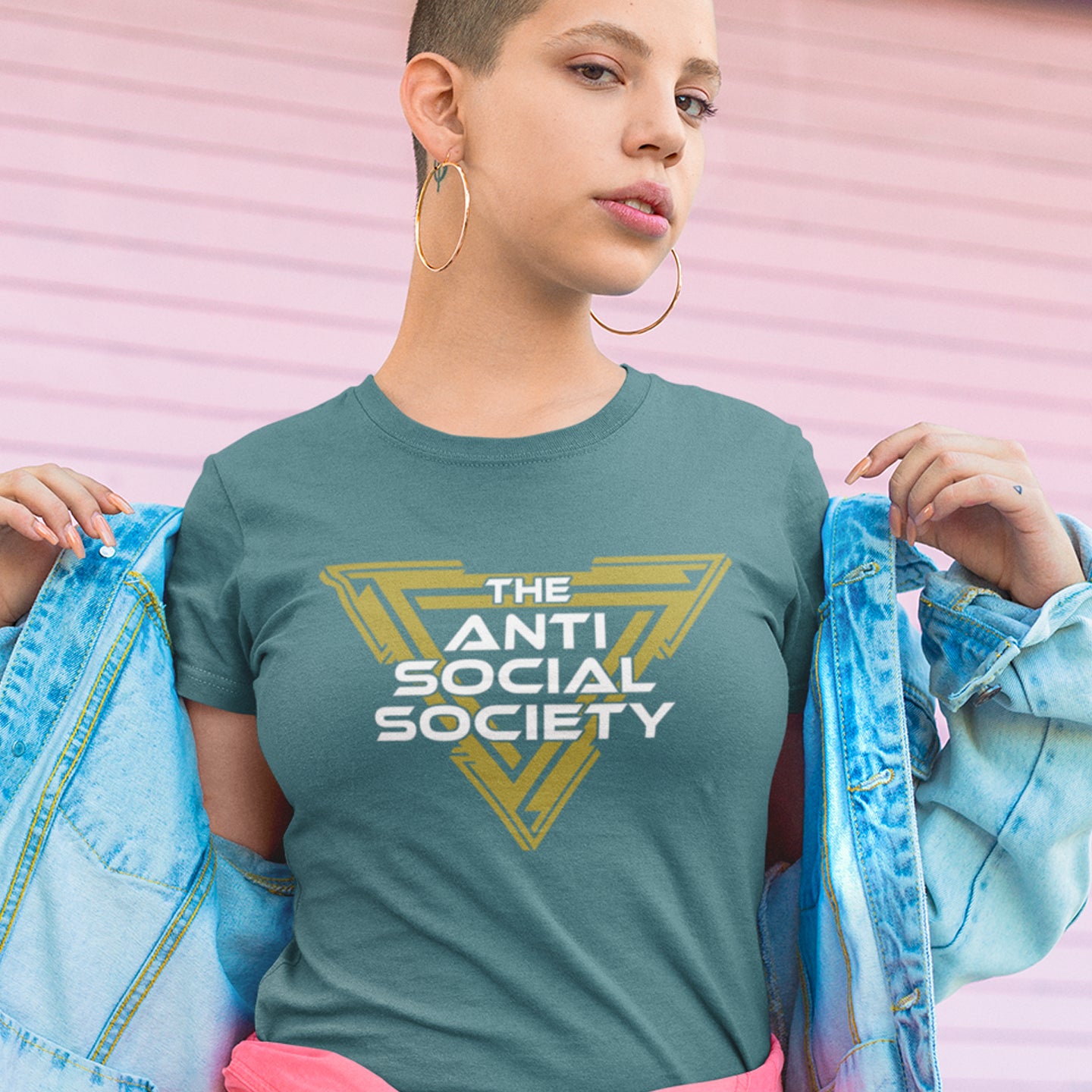 Person wearing a 'The Anti Social Society' t-shirt against a pink background. This anti-social t-shirt design gives you an oxymoron to ponder, the more and more you don't want to be a member, the more you become one. A satirical counterculture dig at modern society Made from 100% organic ring-spun cotton, this social awareness t-shirt is unisex, high-quality, super comfy, and best of all, eco-friendly.