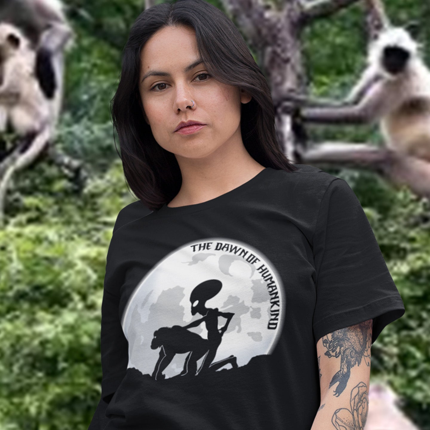 Woman wearing a black t-shirt with a graphic design in front of a natural background. A hilarious alien conspiracy theory t-shirt depicting an one alternative reason for the evolution of humankind on this planet. One of many possibilities as to our origins and why there is such a great distance between us and the rest of the animal kingdom. Made from 100% organic ring-spun cotton, this conspiracy theory t-shirt is unisex, high-quality, super comfy, and best of all, eco-friendly.