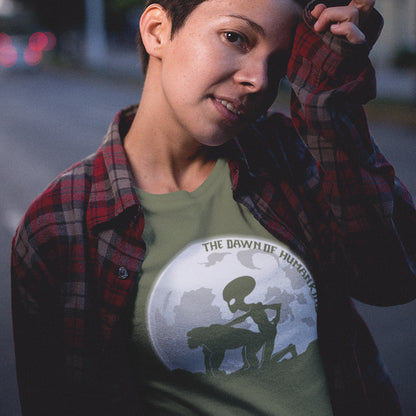 Person wearing a khaki t-shirt with an alien graphic and text, standing outdoors. A hilarious alien conspiracy theory t-shirt depicting an one alternative reason for the evolution of humankind on this planet. One of many possibilities as to our origins and why there is such a great distance between us and the rest of the animal kingdom. Made from 100% organic ring-spun cotton, this conspiracy theory t-shirt is unisex, high-quality, super comfy, and best of all, eco-friendly.