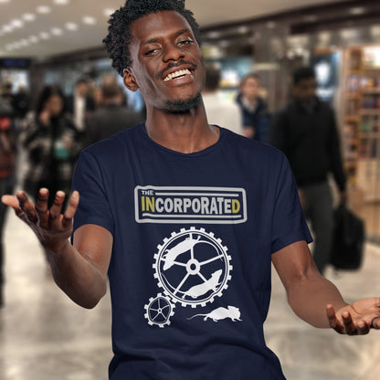 Man wearing a French navy blue t-shirt with 'The Incorporated' logo in a store setting. This non conformist t shirt questions the effects of a corporate run society. Have we just created a corporate cult to follow ? A satirical and alternative view of the modern rat race. Made from 100% organic ring-spun cotton, this counter culture t shirt is unisex, high-quality, super comfy, and best of all, eco-friendly.