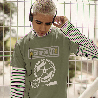 Person wearing a khaki t-shirt with a logo and text, standing in front of a wire fence. This non conformist design questions the effects of a corporate run society in the form of a spoof rock band t shirt. Have we just created a corporate cult to follow ? A satirical and alternative view of the modern rat race. Made from 100% organic ring-spun cotton, this counter culture t shirt is unisex, high-quality, super comfy, and best of all, eco-friendly.