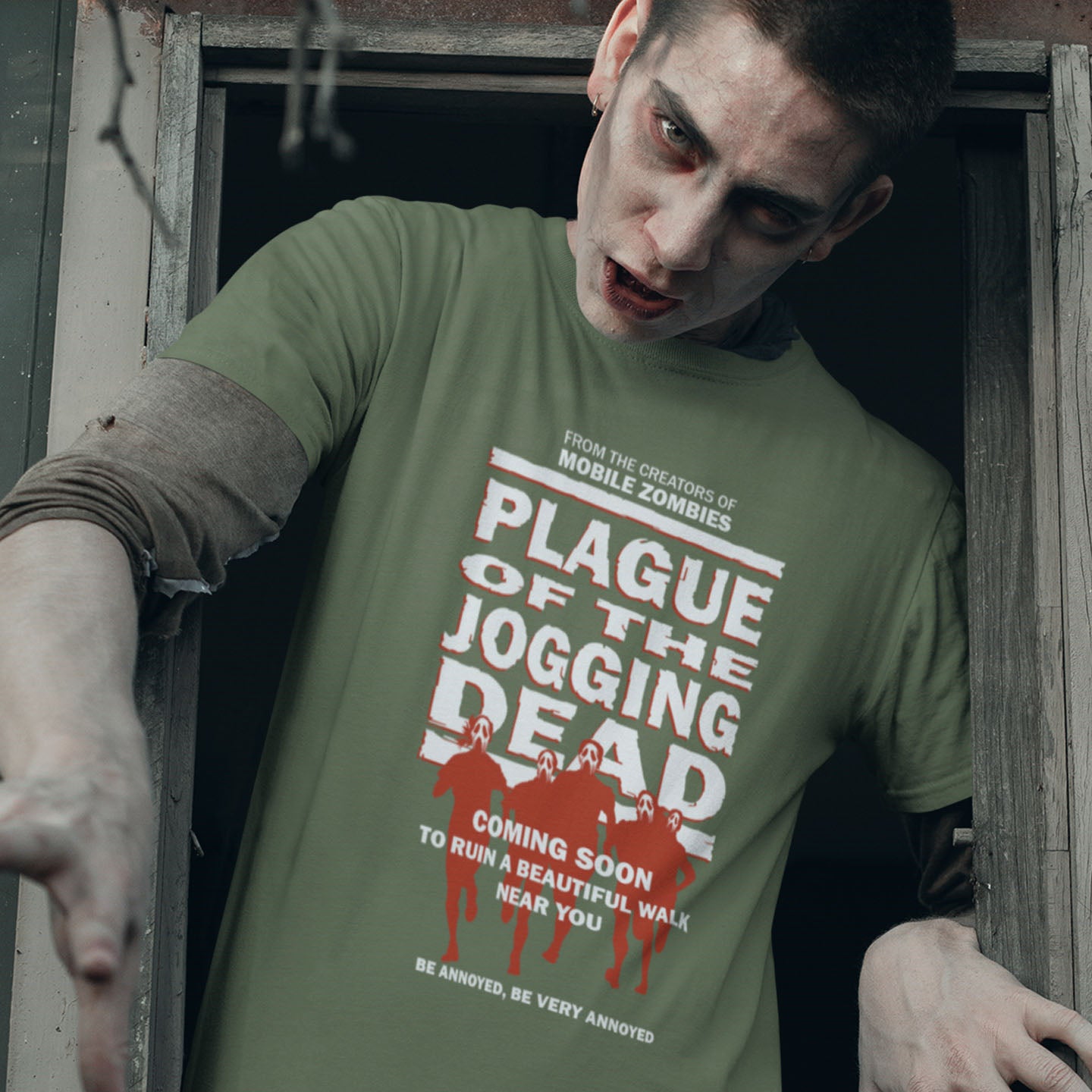 Person wearing a green t-shirt with 'Plague of the Jogging Dead' text and graphics, standing in a doorway. A social issues t shirt about jogging in a horror movie design. Just when you thought it was safe to go out for a nice relaxing walk. Made from 100% organic ring-spun cotton, this social awareness t-shirt is unisex, high-quality, super comfy, and best of all, eco-friendly.