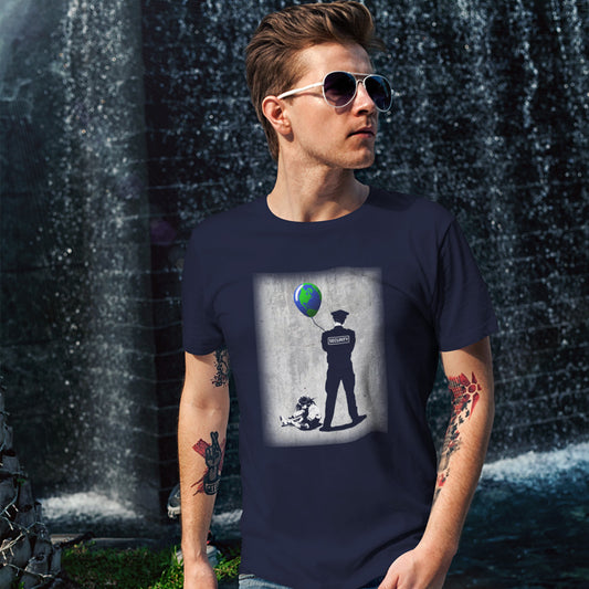 A man in sunglasses and tattoos, standing in front of a water fall, wearing a French navy blue short sleeved crew neck t-shirt with a graffiti stencil design of a girl sitting on the floor, tying her shoelace while a security guard looks after her globe balloon. 