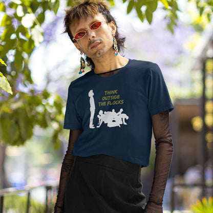 A person outdoors wearing a navy  T-shirt with a white silhouette print and yellow text reading 'THINK OUTSIDE THE FLOCS,' layered over a sheer brown long-sleeve top and black bottoms. This self worth t shirt likens people to sheep. A satirical play on the expression 'Think outside the box'. This dark humour design highlights the need for genuine independent thought. Made from 100% organic ring-spun cotton, this non conformist t shirt is unisex, high quality, super comfy, and best of all, eco-friendly.
