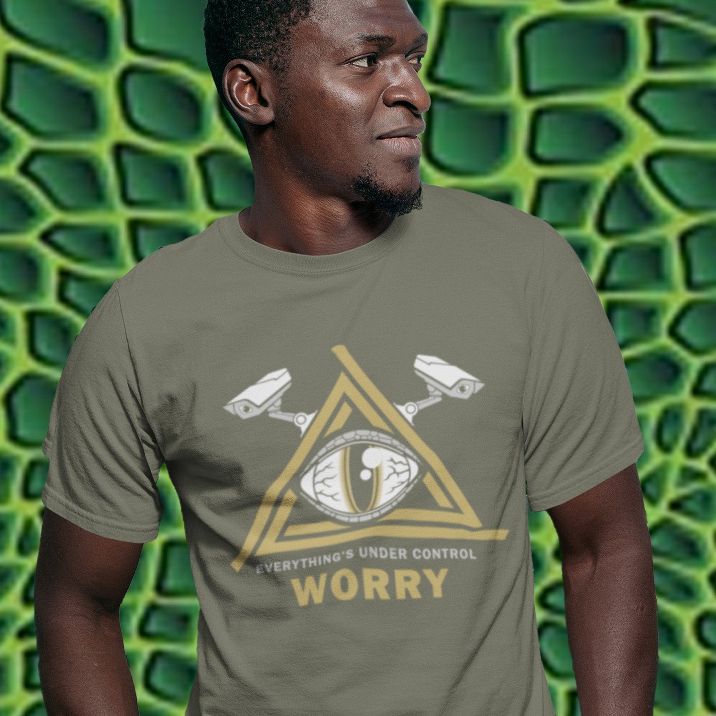 Man wearing a t-shirt with a graphic design and text against a green textured background. A conspiracy theory t-shirt for all that see paranoia as a necessity. This design is a must if your imagination is colourful enough to believe we are being controlled by reptilian alien overlords. Made from 100% organic ring-spun cotton, this alien conspiracy theory t-shirt is unisex, high-quality, super comfy, and best of all, eco-friendly.