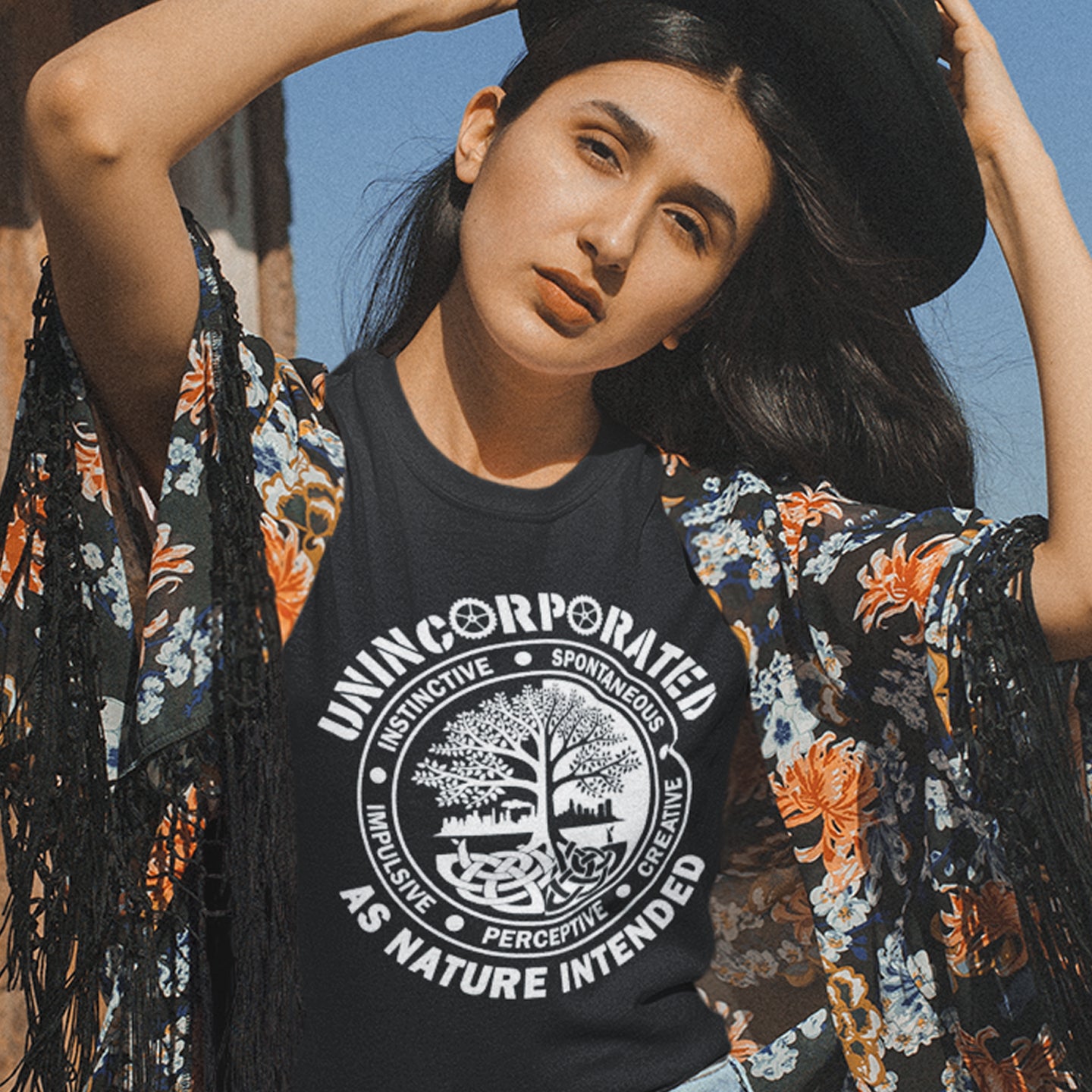 Woman wearing a black t shirt with 'unincorporated' text standing outdoors. This anti corporate t shirt defines corporations as unnatural and indoctrinating. A design for people who are proud to be a human animal and not programmed into the corporate machine. Urban art using the tree of life as a centre piece. Made from 100% organic ring-spun cotton, this non conformist t shirt is unisex, high-quality, super comfy, and best of all—eco-friendly.