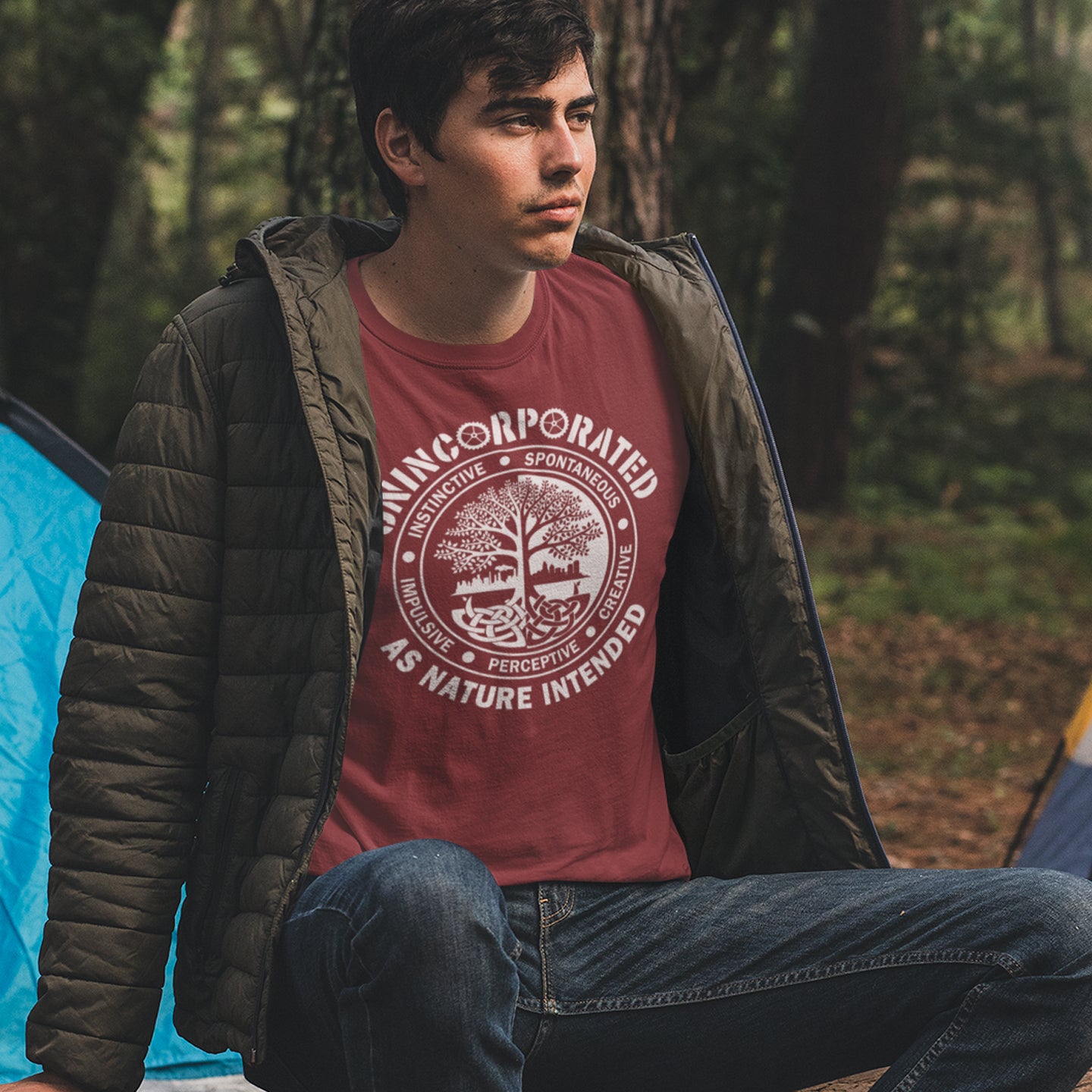 Man camping in the woods wearing a burgundy t shirt with 'unincorporated' text. This anti corporate t shirt defines corporations as unnatural and indoctrinating. A design for people who are proud to be a human animal and not programmed into the corporate machine. Urban art using the tree of life as a centre piece. Made from 100% organic ring-spun cotton, this non conformist t shirt is unisex, high-quality, super comfy, and best of all—eco-friendly.