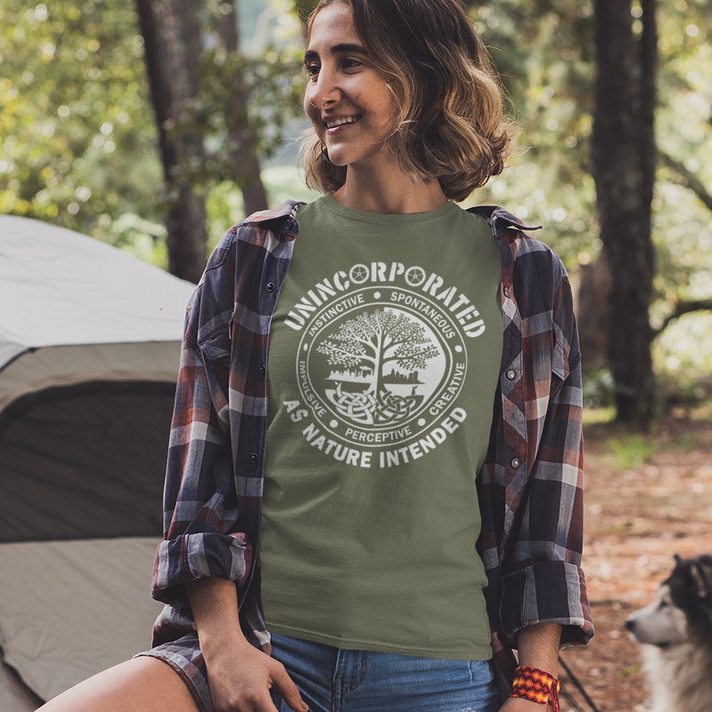 Woman camping in the woods, wearing a khaki t shirt with 'unincorporated' text. This anti corporate t shirt defines corporations as unnatural and indoctrinating. A design for people who are proud to be a human animal and not programmed into the corporate machine. Urban art using the tree of life as a centre piece. Made from 100% organic ring-spun cotton, this non conformist t shirt is unisex, high-quality, super comfy, and best of all—eco-friendly.