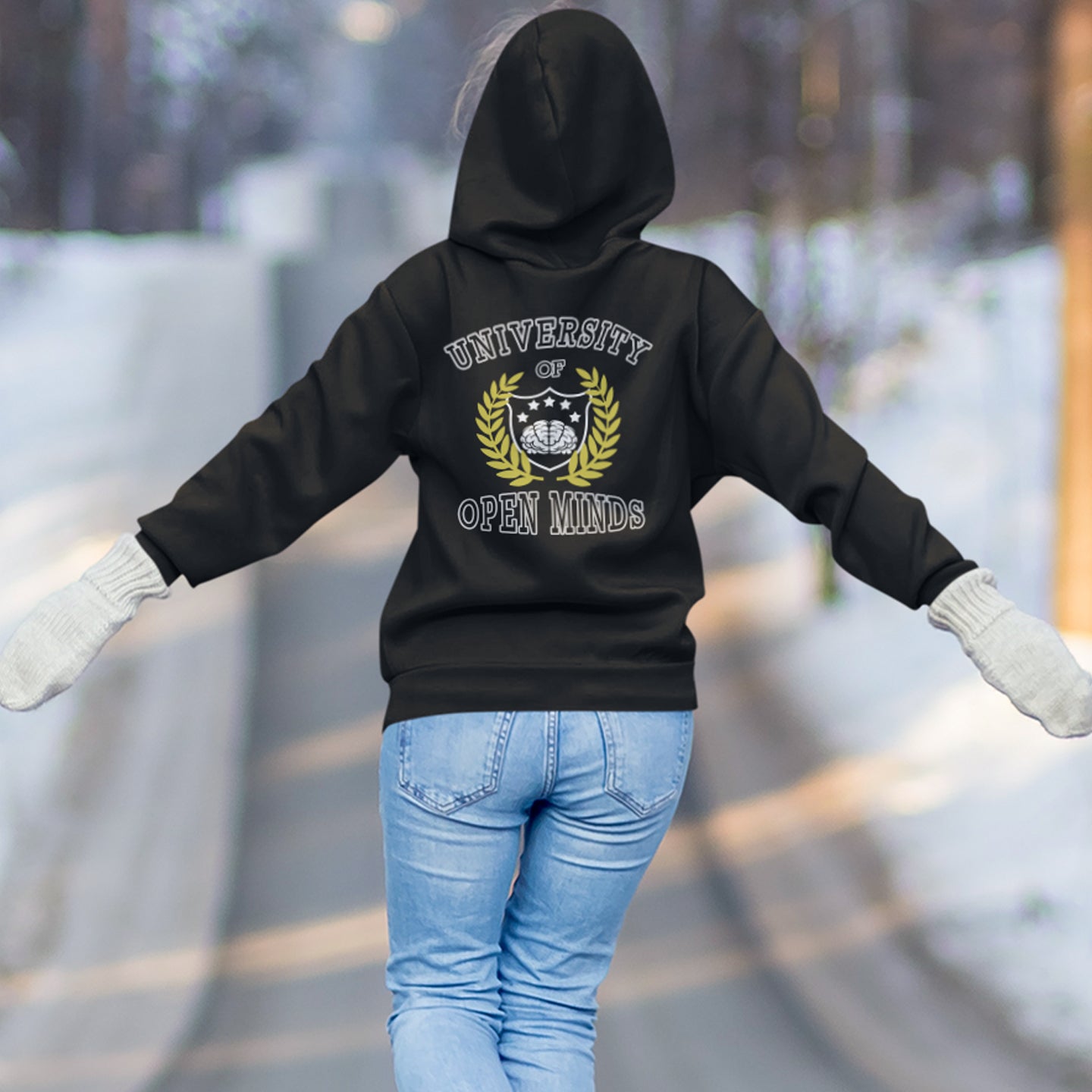 Person wearing a black hoodie with 'University of Open Minds' text and logo, standing outdoors in winter. A graphic hoodie design for the liberal minded. If you think outside the box then this university is for you. Only practical lessons and no student loan required. Comfortable and practical. It's extra soft and has a convenient front pouch pocket. Made from organic cotton and recycled polyester, this graphic hoodie is a great eco-friendly choice.