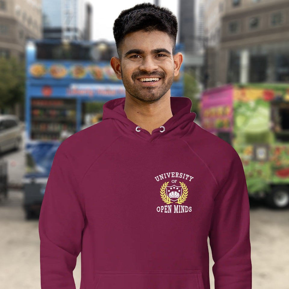 Man wearing a maroon hoodie with 'University of Open Minds' logo in an urban setting. A graphic hoodie design for the liberal minded. If you think outside the box then this university is for you. Only practical lessons and no student loan required. Comfortable and practical. It's extra soft and has a convenient front pouch pocket. Made from organic cotton and recycled polyester, this graphic hoodie is a great eco-friendly choice.