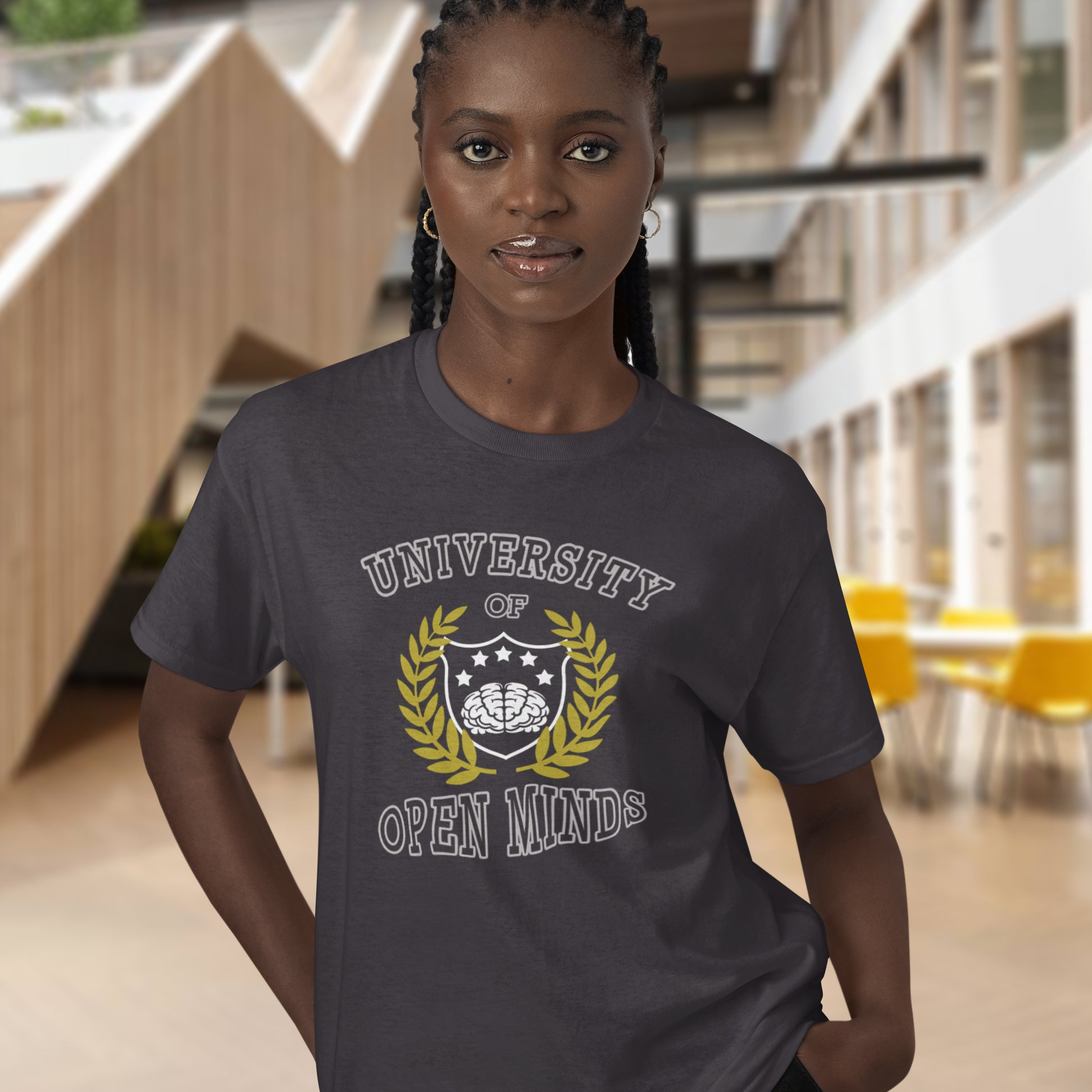 Person wearing a t-shirt with 'University of Open Minds' design in an indoor setting. A cool graphic design for the liberal minded. If you think outside the box then this university is for you. Only practical lessons and no student loan required. Made from 100% organic ring-spun cotton, this social awareness t-shirt is unisex, high-quality, super comfy, and best of all, eco-friendly.