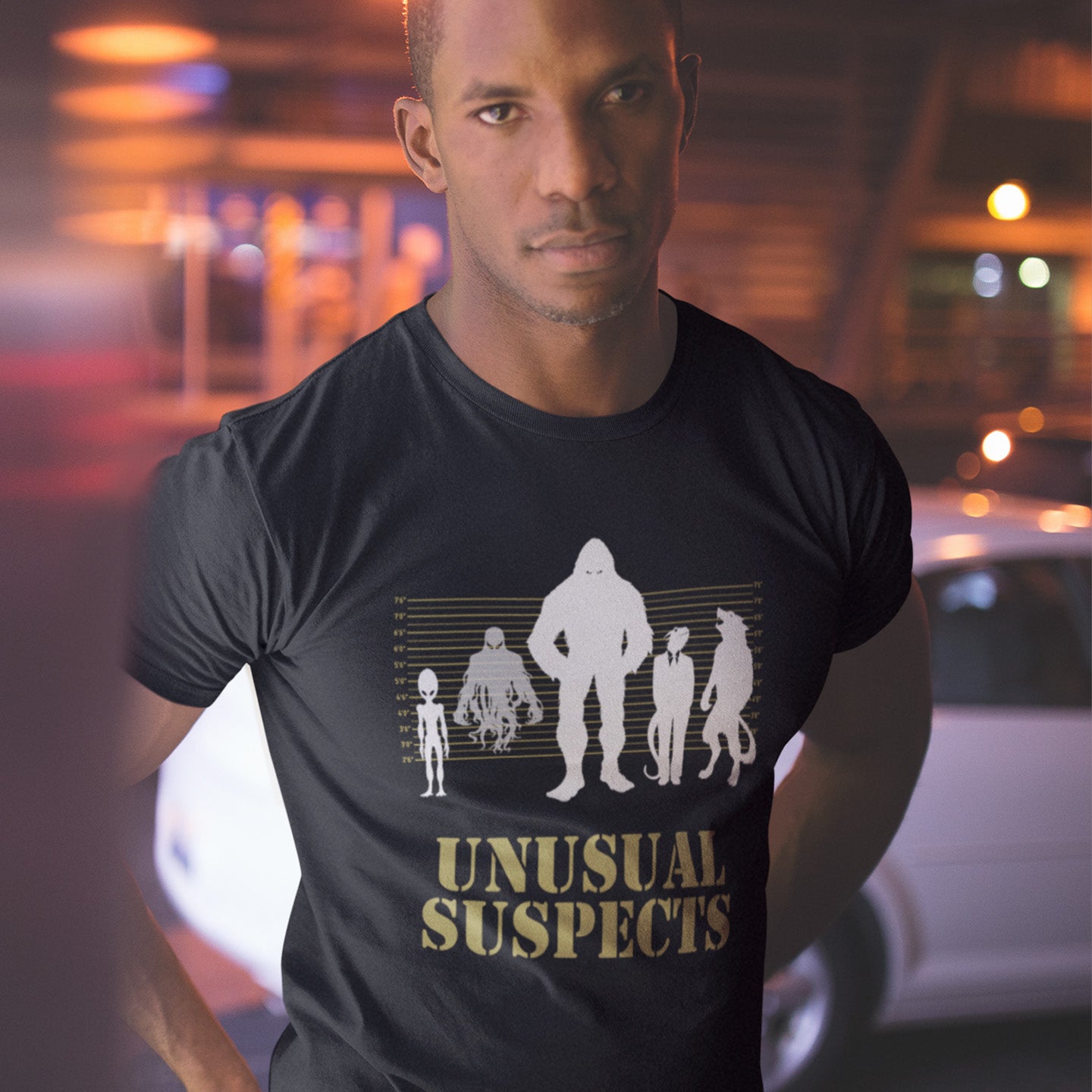 Man wearing a black t-shirt with 'Unusual Suspects' graphic design. A conspiracy theorist t shirt for movie lovers. From bigfoot to aliens, these are the personnel responsible for most cover ups and disputed existences. This imaginative stencil art design is for people who think outside the box. Made from 100% organic ring-spun cotton, this witty conspiracy theory t-shirt is unisex, high-quality, super comfy, and best of all, eco-friendly.