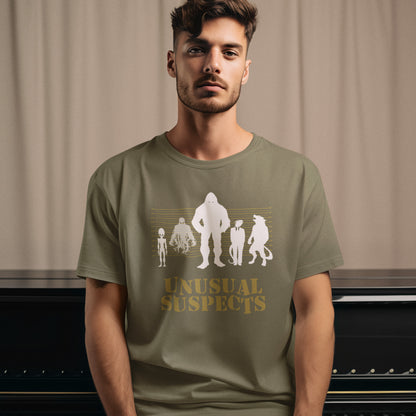 Man wearing a khaki t-shirt with 'Unusual Suspects' graphic design. A conspiracy theorist t shirt for movie lovers. From bigfoot to aliens, these are the personnel responsible for most cover ups and disputed existences. This imaginative stencil art design is for people who think outside the box. Made from 100% organic ring-spun cotton, this witty conspiracy theory t-shirt is unisex, high-quality, super comfy, and best of all, eco-friendly.
