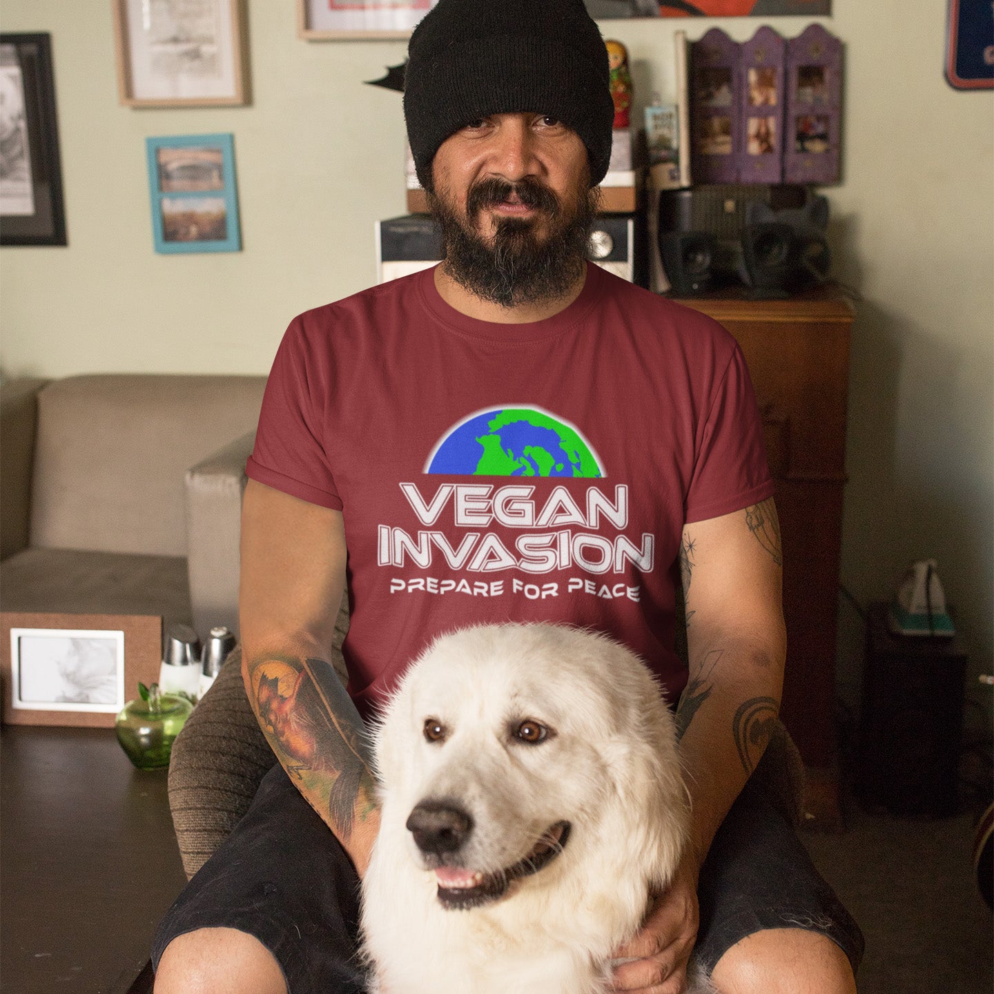 Man wearing a 'Vegan Invasion' t-shirt with a dog sitting on his lap in a living room. This vegan meat free t shirt design plays on the idea that other people view vegans as alien. Reassure people that you are a peaceful creature and remind them that you help to save the planet. Made from 100% organic ring-spun cotton, this plant based meat free t shirt is unisex, high-quality, super comfy, and best of all, eco-friendly.