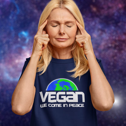 Person wearing a French navy blue t-shirt with 'Vegan We Come in Peace' text and logo on a purple galaxy background.  This vegan dairy free t shirt design is for any vegan who feels like they are seen as an alien by others. Reassure people that you are a peaceful creature and want to save the planet. Made from 100% organic ring-spun cotton, this plant based meat free t shirt is unisex, high-quality, super comfy, and best of all, eco-friendly.