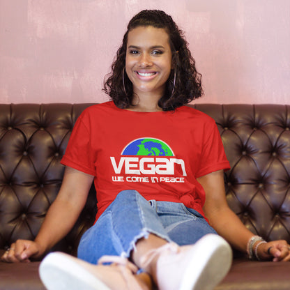 Person wearing a red 'VEGAN WE COME IN PEACE' t-shirt sitting on a brown leather couch.  This vegan dairy free t shirt design is for any vegan who feels like they are seen as an alien by others. Reassure people that you are a peaceful creature and want to save the planet. Made from 100% organic ring-spun cotton, this plant based meat free t shirt is unisex, high-quality, super comfy, and best of all, eco-friendly.