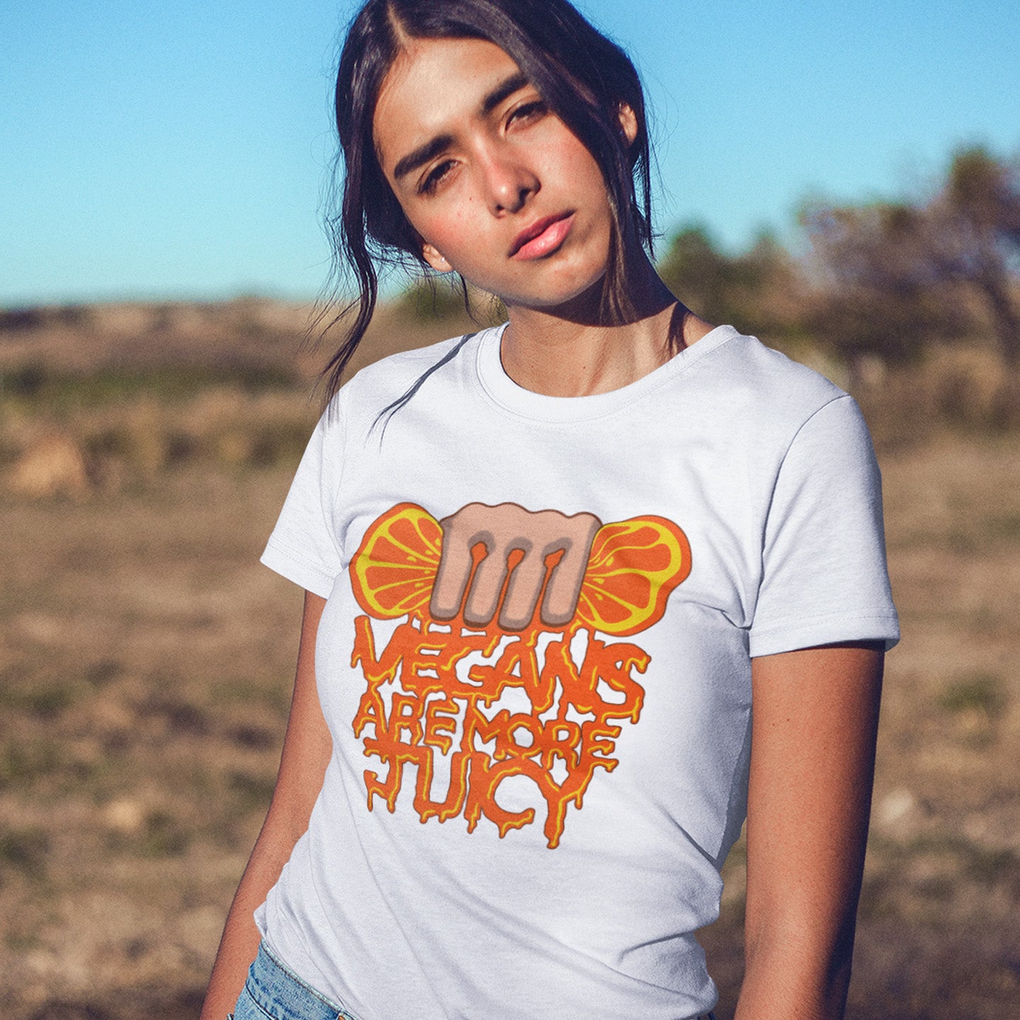 Person wearing a white t-shirt with a graphic design and text outdoors. A plant based meat free t shirt design suggesting vegans drink more juices than most. Made from 100% organic ring-spun cotton, this vegan dairy free t shirt is unisex, high-quality, super comfy, and best of all, eco-friendly.