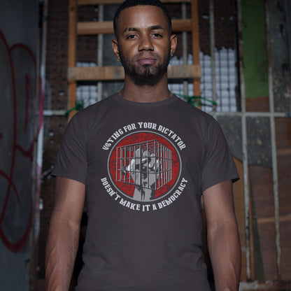 A man wearing a dark gray graphic t-shirt with a red and white circular design featuring a portrait and text, set against a gritty urban alley background.