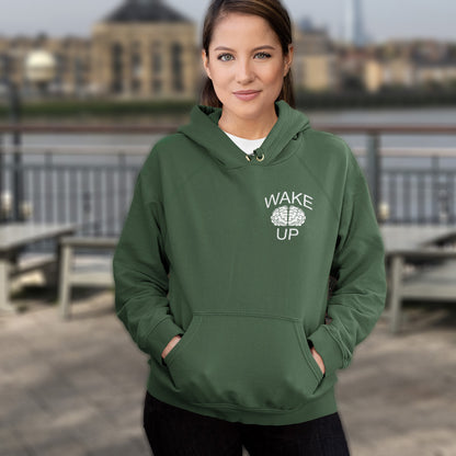 Woman wearing a bottle green hoodie with 'Wake Up' text, standing outdoors. This satirical 'stay calm' anti establishment hoodie suggests we have been calm too long and need of waking up and panic. Keeping calm got us into this mess, it's time to wake up. Comfortable and practical. It's extra soft and has a convenient front pouch pocket. Made from organic cotton and recycled polyester, this activist hoodie is a great eco-friendly choice.