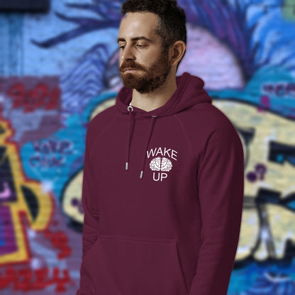 Man wearing a burgundy hoodie with 'Wake Up' text, standing in front of a colourful graffiti wall. This satirical 'stay calm' anti establishment hoodie suggests we have been calm too long and need of waking up and panic. Keeping calm got us into this mess, it's time to wake up. Comfortable and practical. It's extra soft and has a convenient front pouch pocket. Made from organic cotton and recycled polyester, this activist hoodie is a great eco-friendly choice.