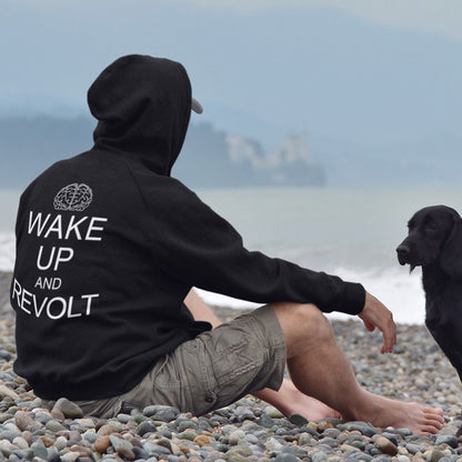 Person wearing a black hoodie with 'Wake Up and Revolt' text sitting on a pebbly beach with a dog. This satirical 'stay calm' hoodie suggests we have been calm too long and need of waking up and fighting for our right instead. Keeping calm got us into this mess, it's time to wake up. Comfortable and practical. It's extra soft and has a convenient front pouch pocket. Made from organic cotton and recycled polyester, this anti-establishment hoodie is a great eco-friendly choice.