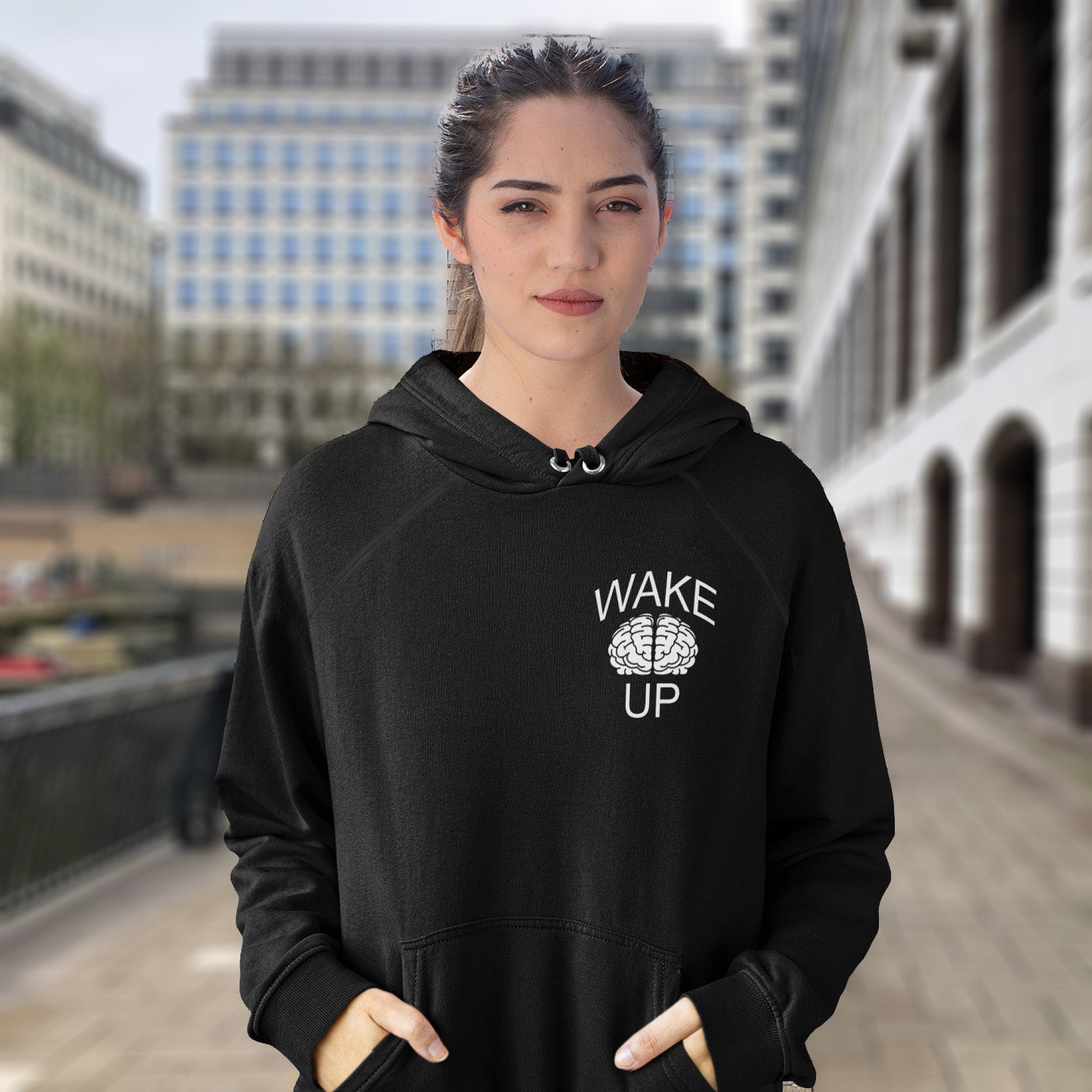 Person wearing a black hoodie with 'Wake Up' text in an urban setting. This satirical 'stay calm' hoodie suggests we have been calm too long and need of waking up and fighting for our right instead. Keeping calm got us into this mess, it's time to wake up. Comfortable and practical. It's extra soft and has a convenient front pouch pocket. Made from organic cotton and recycled polyester, this anti-establishment hoodie is a great eco-friendly choice.