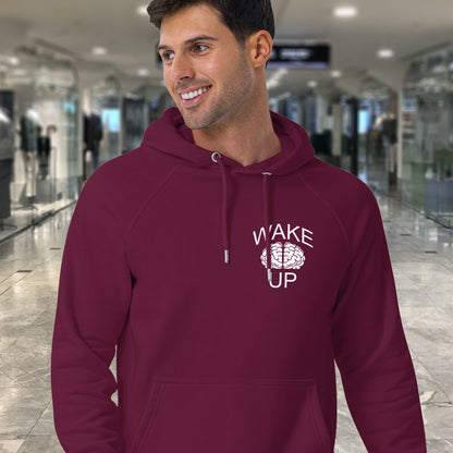 Man wearing a burgundy
 hoodie with 'Wake Up' text in a modern indoor. This satirical 'stay calm' hoodie suggests we have been calm too long and need of waking up and fighting for our right instead. Keeping calm got us into this mess, it's time to wake up. Comfortable and practical. It's extra soft and has a convenient front pouch pocket. Made from organic cotton and recycled polyester, this anti-establishment hoodie is a great eco-friendly choice. setting