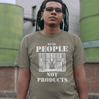 Man with dreadlocks standing outside, wearing a khaki 'we're people not products' t shirt. An anti capitalism t shirt highlighting the dehumanisation of people in a money obsessed society. A fantastic choice for any anti capitalism protest or to just create social awareness. Made from 100% organic ring-spun cotton, this anti consumerism t shit is unisex, high-quality, super comfy, and best of all, eco-friendly.
