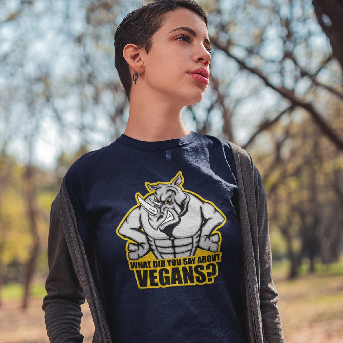 A woman standing in the forest wearing a French navy blue crew neck t-shirt with a cartoon Rhino design and the caption "WHAT DID YOU SAY ABOUT VEGANS?".
