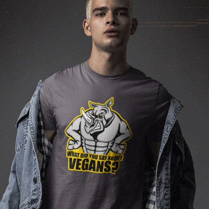 A man standing against a grey wall, wearing an anthracite grey crew neck t-shirt with a cartoon Rhino design and the caption "WHAT DID YOU SAY ABOUT VEGANS?".