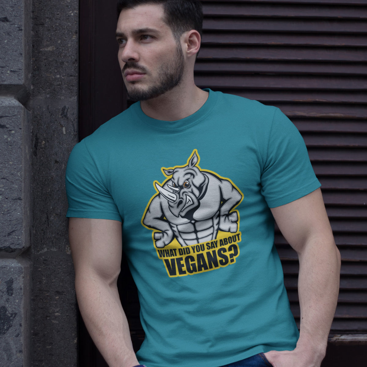 A muscular man stood in a door way, wearing a stargazer blue short sleeved crew neck t-shirt with a cartoon Rhino design and the caption "WHAT DID YOU SAY ABOUT VEGANS?".