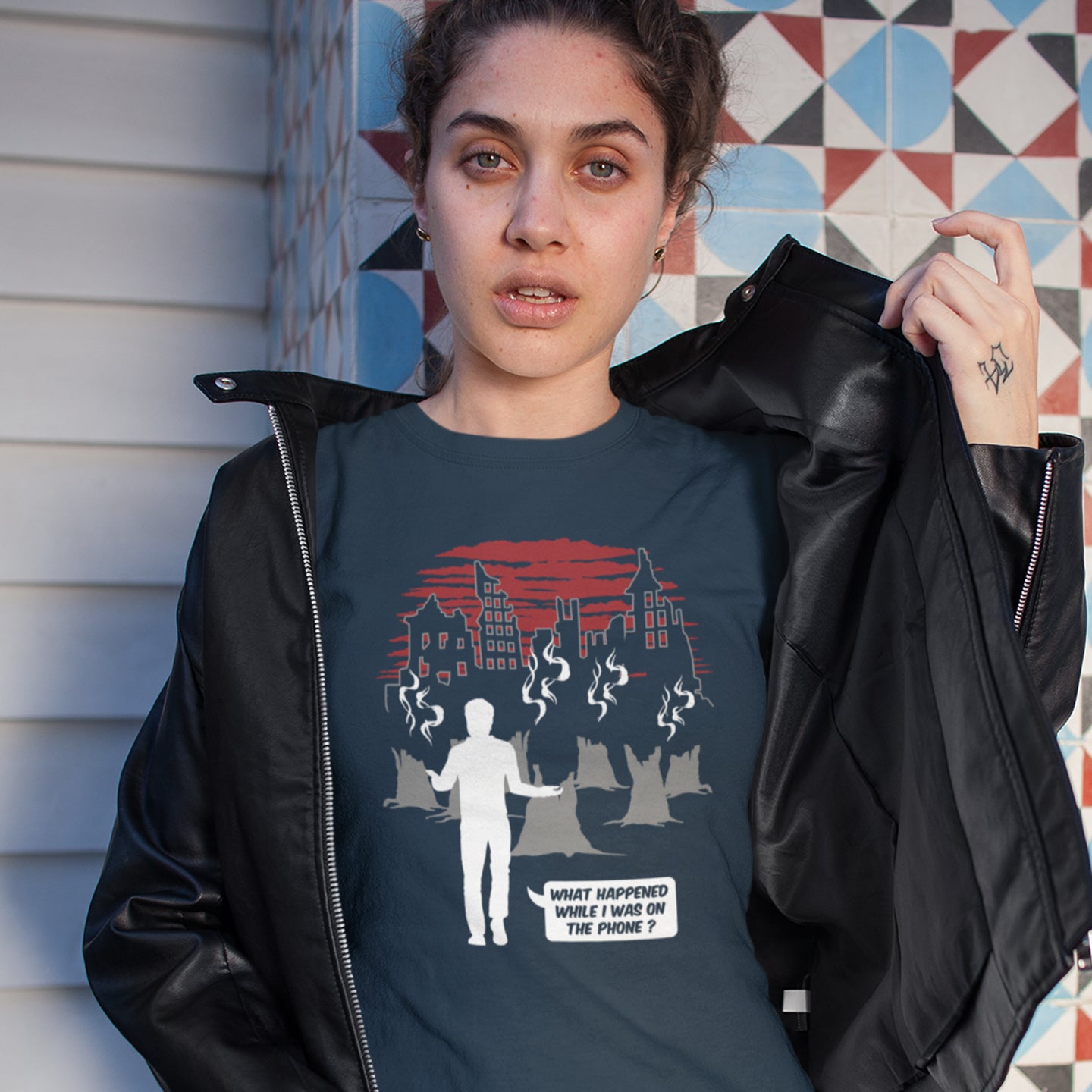Person wearing a dark blue t-shirt with graphic design and text, standing against a colorful geometric-patterned wall. This environmental concern t-shirt asks the question Is the mobile phone the ultimate distraction from the real issues going on in the World. Let's put down the phone and save the planet. Climate concern is not an app. Made from 100% organic ring-spun cotton, this social awareness &amp; environmental concern t-shirt is unisex, high-quality, super comfy, and best of all, eco-friendly.
