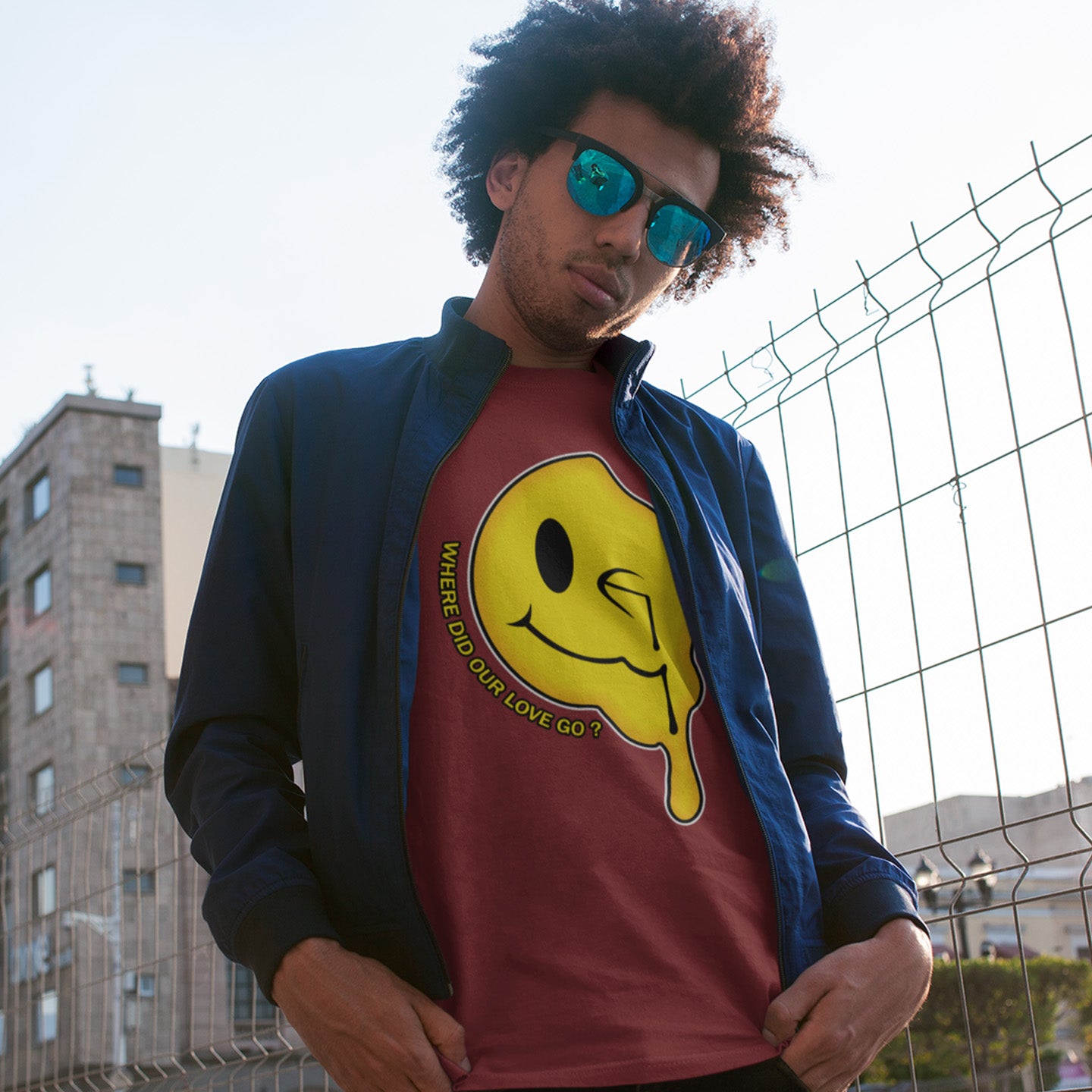Person wearing a burgundy shirt with a yellow smiley face graphic and blue jacket, standing in front of a wire fence. An old skool 90's acid house t shirt. This design is a tribute to 90's house music and the love that was felt around the scene. What happened ? Made from 100% organic ring-spun cotton, this 90's acid house t shirt is unisex, high-quality, super comfy, and best of all, eco-friendly.