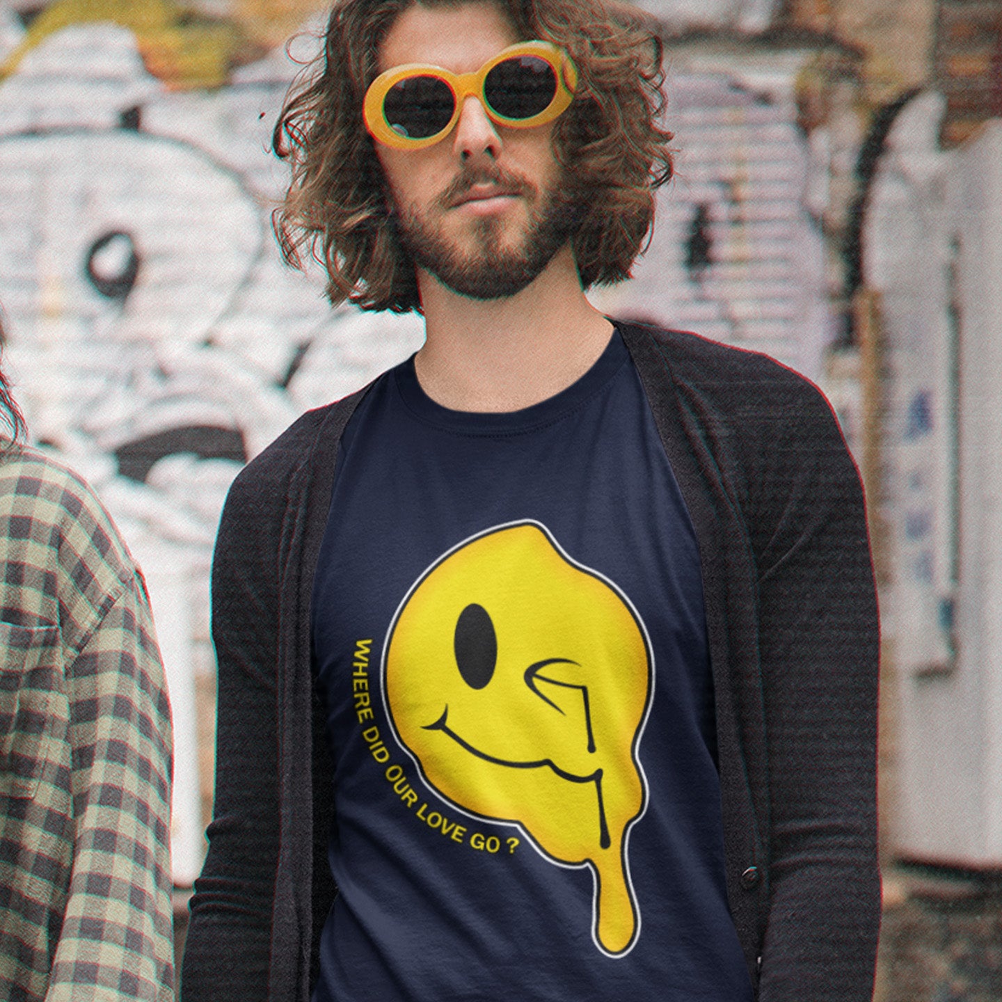 Man wearing a French navy blue t-shirt with a yellow graphic design in an urban setting. A old skool acid house t-shirt. This design is a tribute to 90's house music and the love that was felt around the scene. What happened ? Made from 100% organic ring-spun cotton, this acid house t-shirt is unisex, high-quality, super comfy, and best of all, eco-friendly.