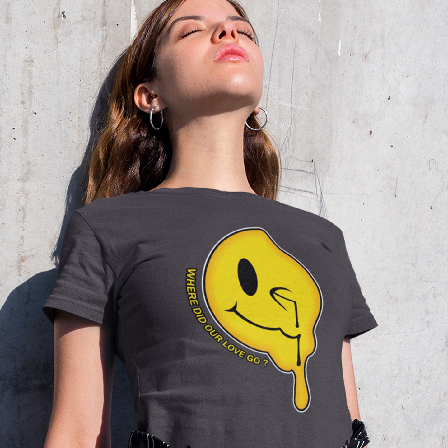 Person wearing an anthracite t-shirt with a yellow smiley face graphic and text against a concrete wall. A old skool acid house t-shirt. This design is a tribute to 90's house music and the love that was felt around the scene. What happened ? Made from 100% organic ring-spun cotton, this acid house t-shirt is unisex, high-quality, super comfy, and best of all, eco-friendly.